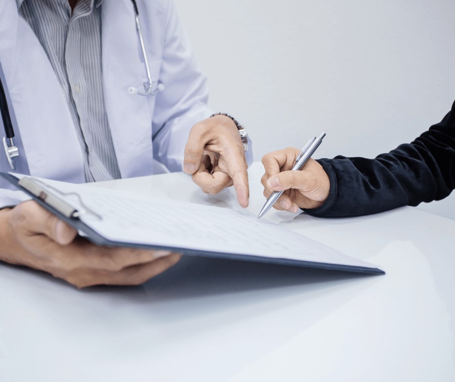 Two people, one is about to sign a document while the other points at where they should sign.