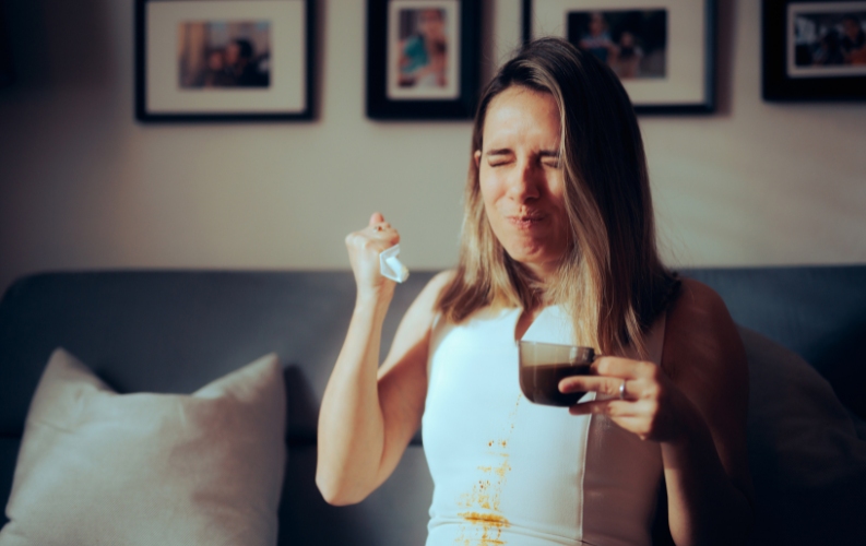 A person has spilled coffee on themselves and they are not happy.
