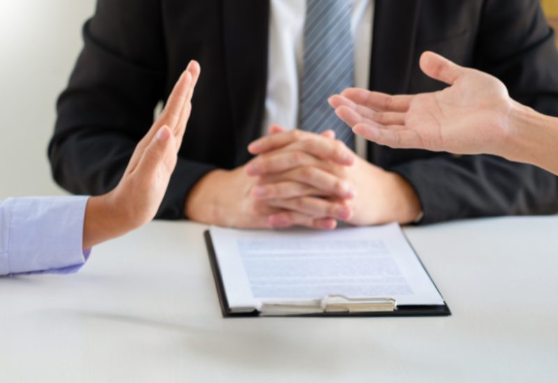 A mediator facilitating a civil dispute resolution at a table, with documents and notes visible from Wallace Smith Lawyers